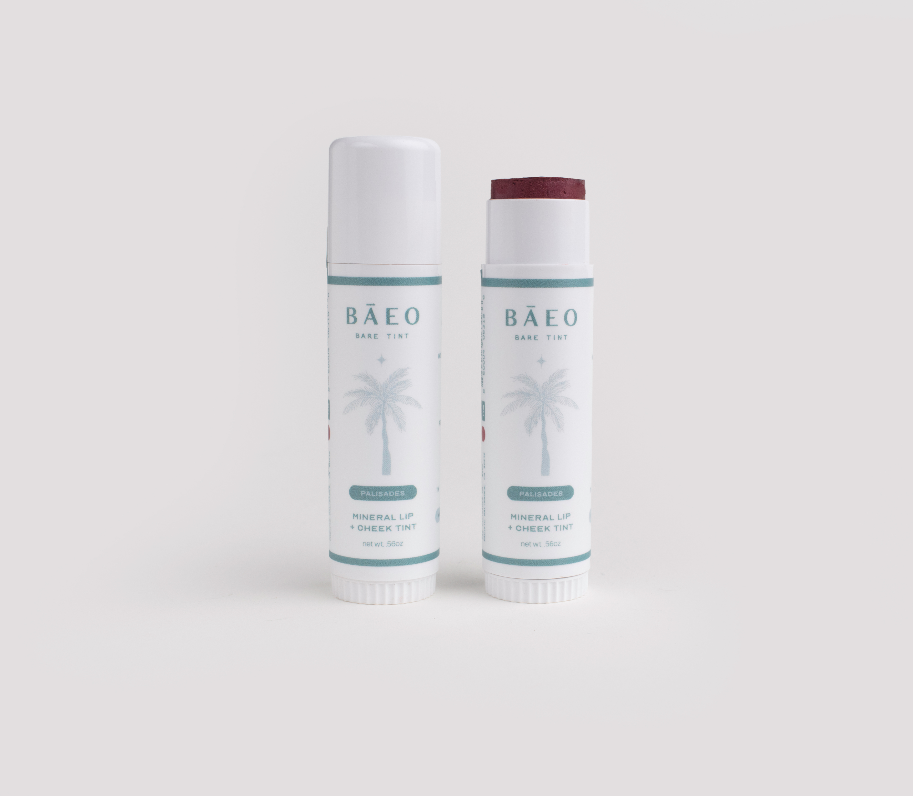 Two bāeo bare tint 'palisades' tubes, labeled "Mineral Lip + Cheek Tint" with a palm tree on the white label, stand side by side—one capped, one open to reveal a deep red hydrating tint for buildable color and a natural dewy finish.