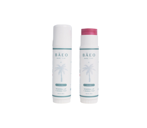 Two tubes of bāeo bare tint 'malibu' Mineral Lip & Cheek Tint; one open to reveal a pink shade. Both have white packaging with a light blue palm tree, representing their plant-based formula.