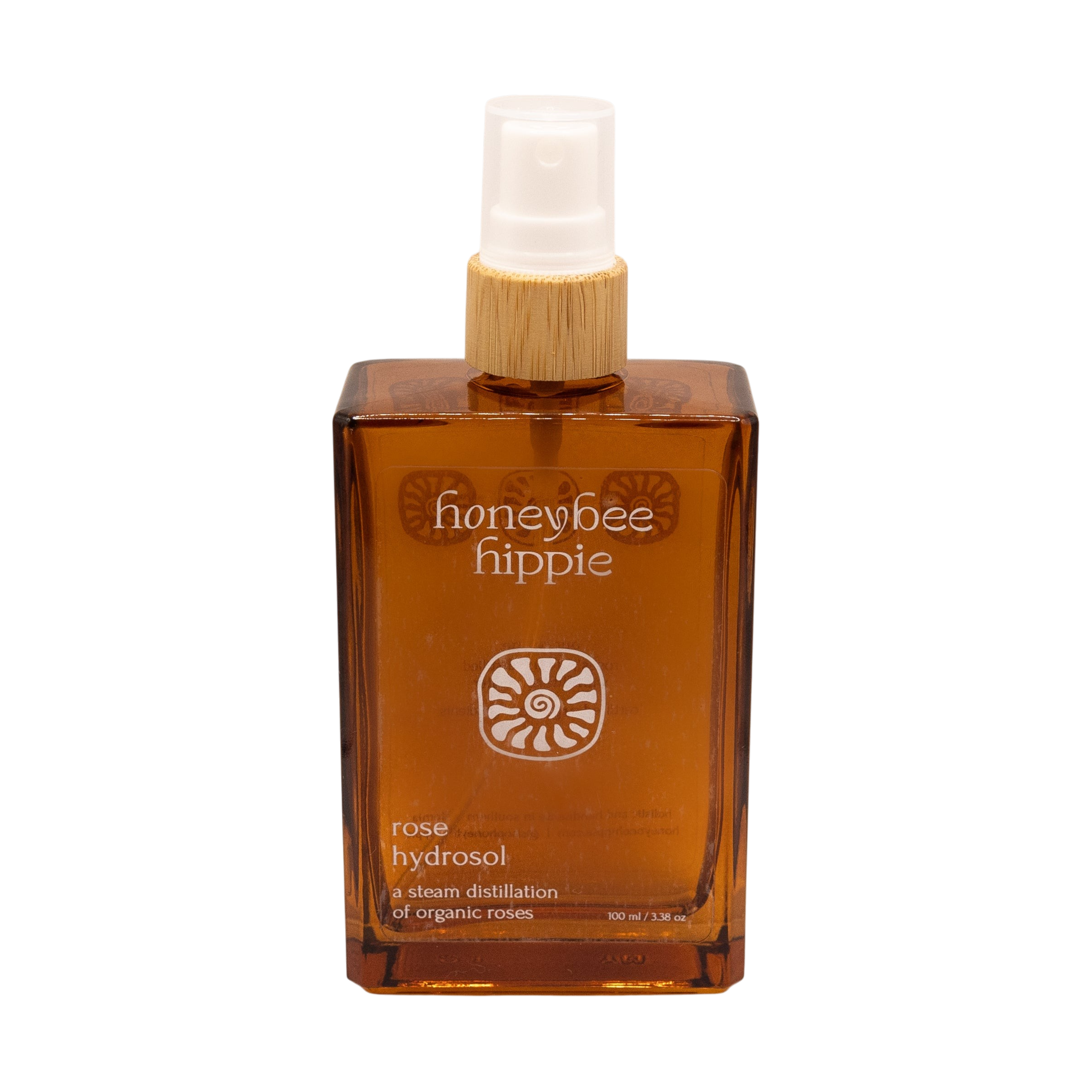 A brown rectangular spray bottle labeled "Honeybee Hippie rose hydrosol" with white text, sun-like symbols, a white spray nozzle, and a wooden collar—ideal as a natural toner or skin refresher.