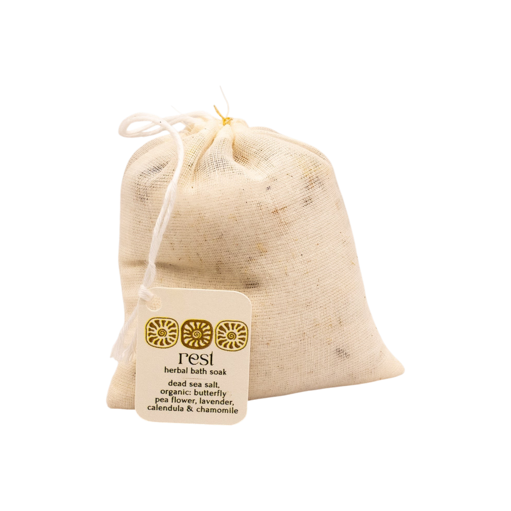 The "rest bath soak" by Honeybee Hippie is a small muslin drawstring bag featuring Dead Sea salt and botanicals like butterfly pea flower, lavender, calendula, and chamomile—a treat for botanical skincare lovers.