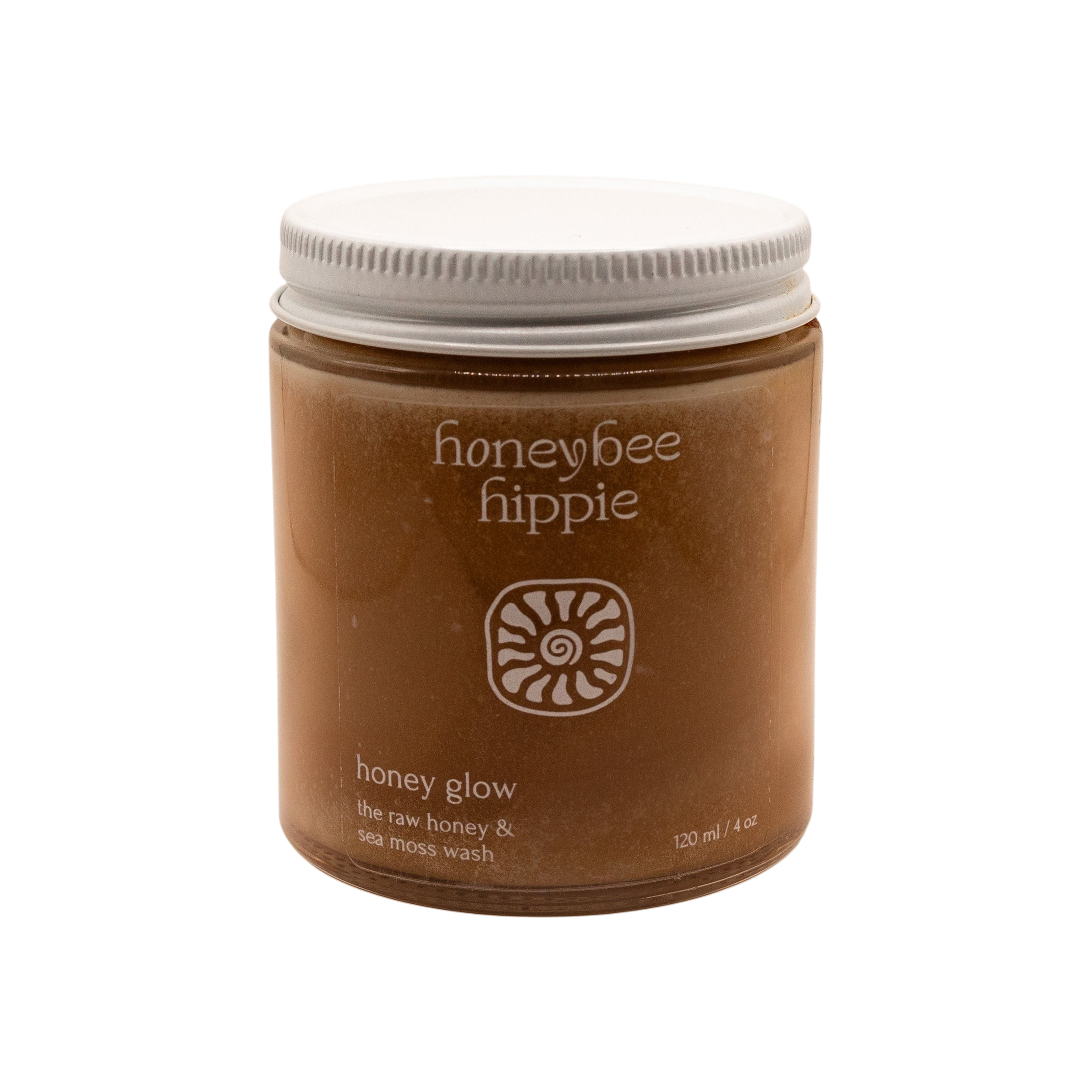 A minimalist brown jar with a white lid, labeled "Honeybee Hippie" and "honey glow," contains raw honey and sea moss wash—a gentle, soap-free facial cleanser—displayed against a plain white background.