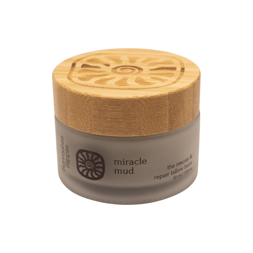 A small frosted glass jar with a wooden lid labeled "miracle mud" by Honeybee Hippie displays a spiral sun, offering skin comfort as a herbal balm enriched with bentonite clay for rescue and repair.