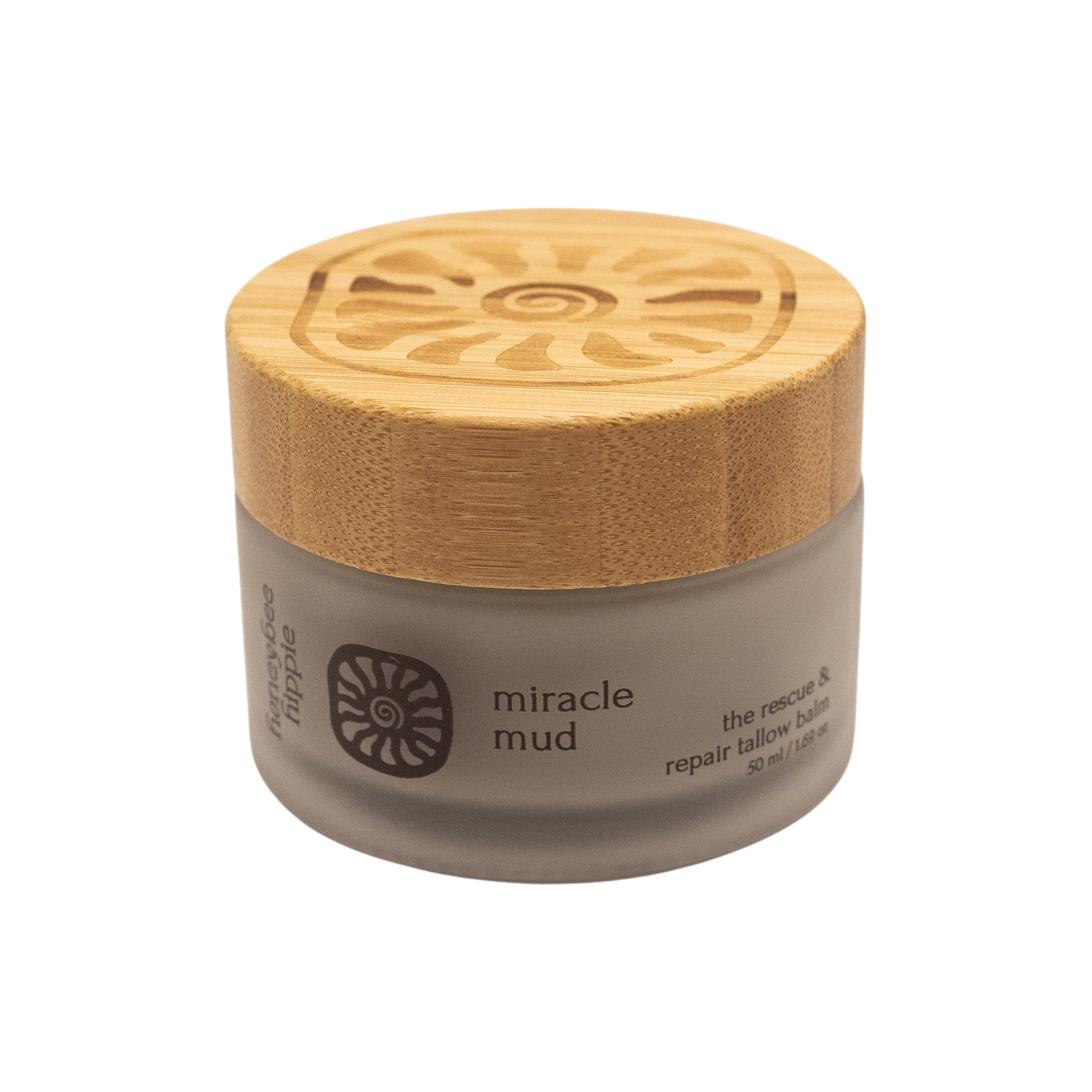 A small frosted glass jar with a wooden lid labeled "miracle mud" by Honeybee Hippie displays a spiral sun, offering skin comfort as a herbal balm enriched with bentonite clay for rescue and repair.