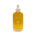 A clear glass bottle of golden yellow hair oil with a white dropper cap; the label reads "Honeybee Hippie" and "sacred shine hair oil" with additional text below.