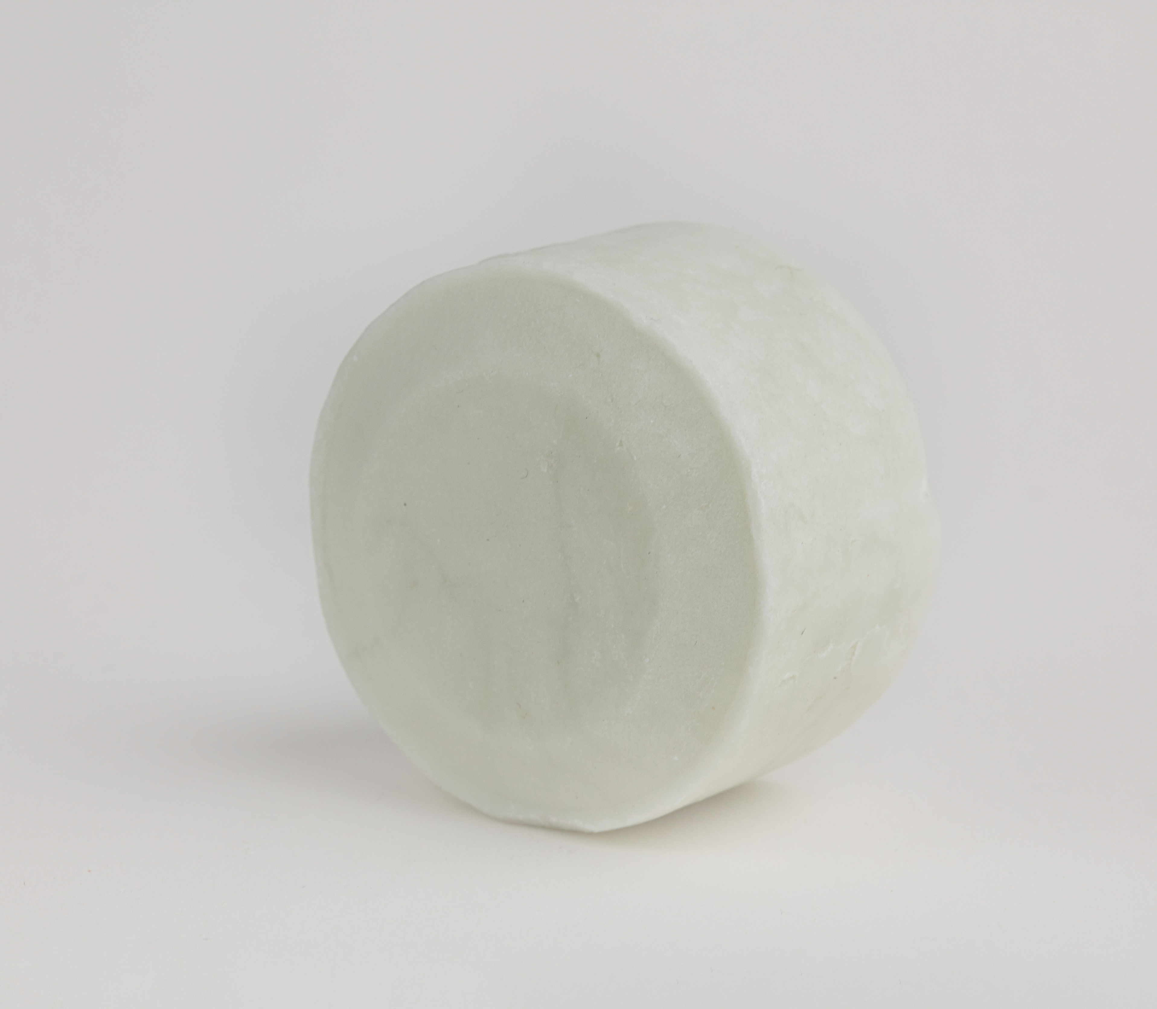 The bāeo bare bar, a round white shampoo and body wash bar, stands upright against a plain background, providing gentle cleansing with nourishing plant-based oils.