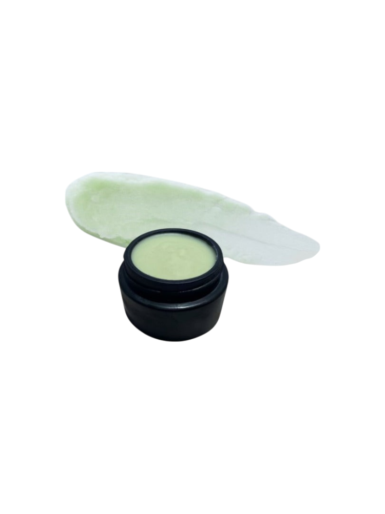 A small black jar of Ancestral Blue 2.4oz by Wild Mamas, filled with light green cream made from grass-fed tallow, sits in front of a smear of the same cream on a white background.
