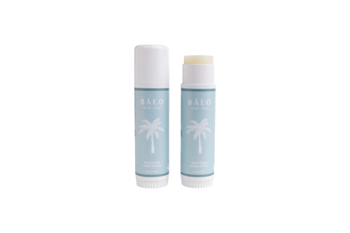 Two light blue tubes of bāeo bare face hydrating stick, with white palm tree graphics—one open to reveal the balm, one closed—are shown on a white background. Made with organic botanicals for gentle skin care.