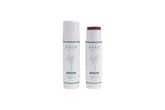 Two tubes of bāeo bare tint 'palisades'—one capped, one open to reveal the tint—both with palm tree graphics and minimalist white labels, showcasing fresh, buildable color for lips and cheeks.