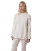 A person with long blonde hair wears Wol Hide's Big Sweatshirt in Natural, paired with matching pants, and stands against a plain white background.