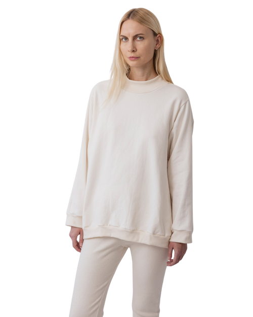 A person with long blonde hair wears Wol Hide's Big Sweatshirt in Natural, paired with matching pants, and stands against a plain white background.