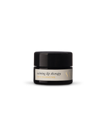 A small black jar of Surya's Calming Lip Therapy rests on a plain white background, featuring an organic lip balm crafted for soothing comfort.