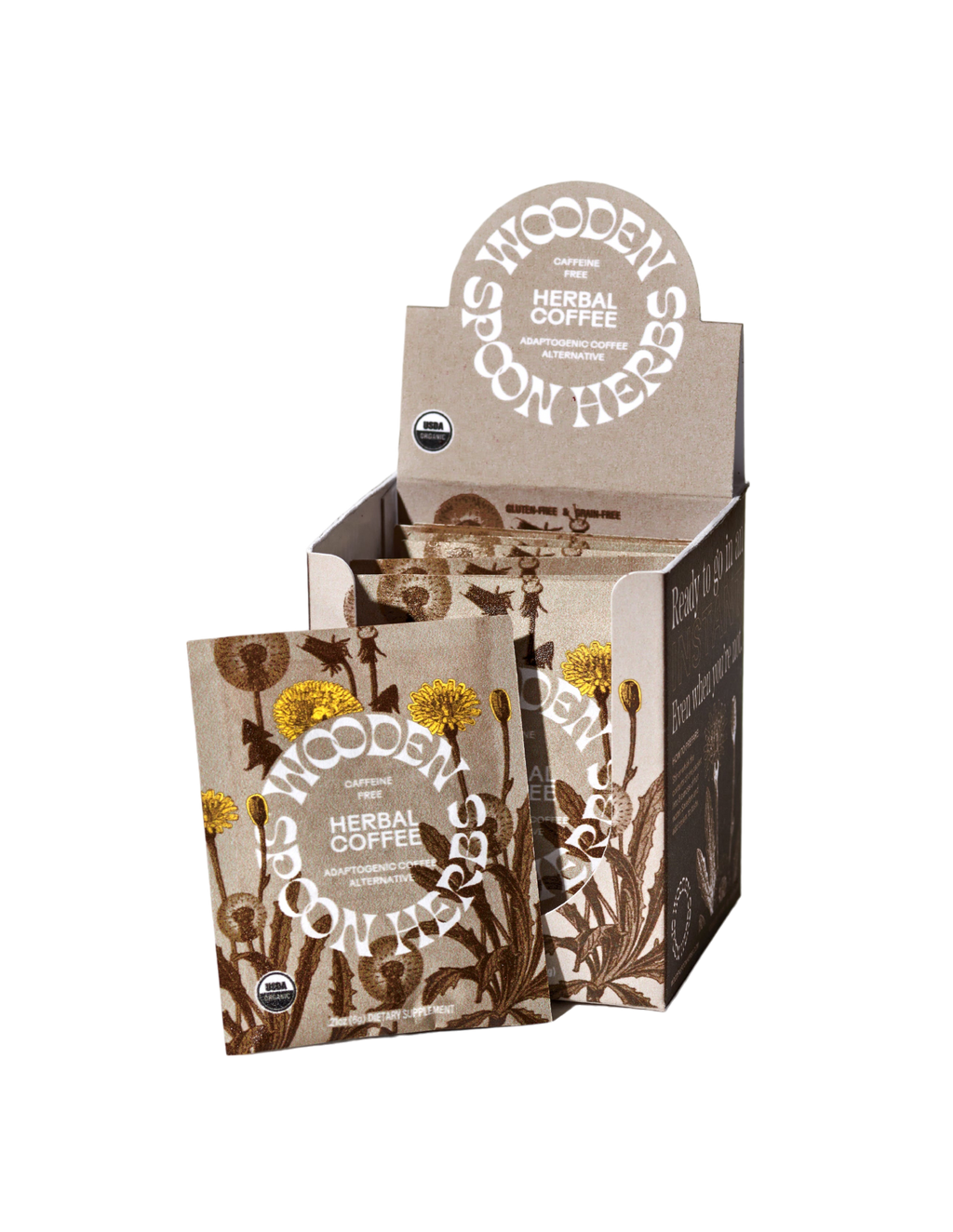 A product display box of WOODEN SPOON HERBS Herbal Coffee, highlighting a caffeine-free blend with multiple individual packets. The packaging features illustrations of dandelion and other plants in a natural earthy color scheme, with text indicating USDA organic certification and the inclusion of adaptogenic mushrooms.