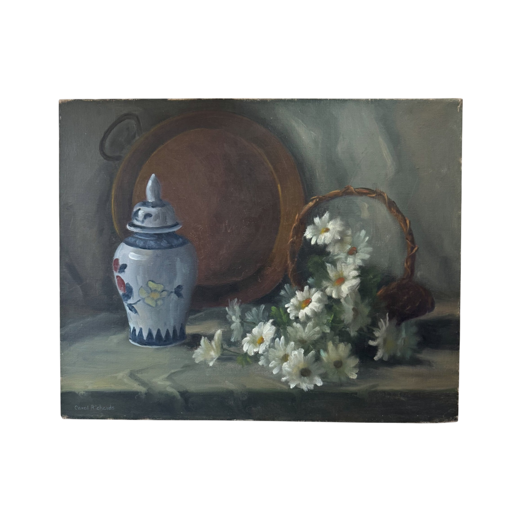 The Carol Richards Still Life from Shoppe Maison features a blue and white jar, an antique basket of daisies, and a round brown tray set on draped green cloth.