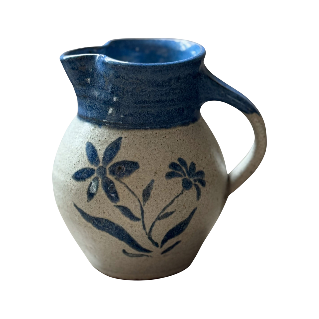 The Shoppe Maison Stoneware Creamer features a handmade salt-glazed ceramic style with a blue-glazed rim and handle, decorated with hand-painted blue flowers on a beige background.