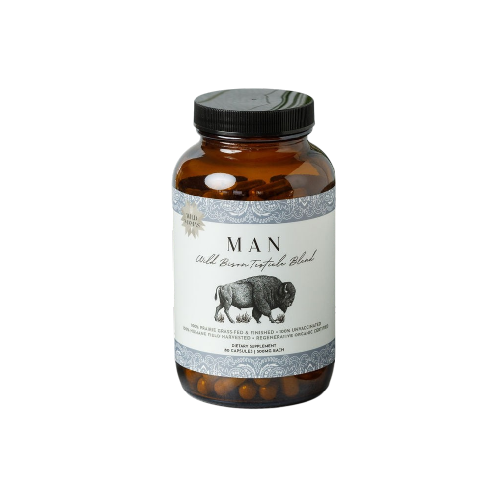 A clear jar with a black lid labeled "Man - Wild Bison Testicle Organ Blend" by Wild Mamas. The label shows a bison, describing this wild-harvested, regenerative supplement as ideal for natural testosterone support. Brown capsules are visible inside.