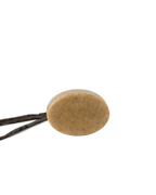 The Wild Mamas Madagascar Vanilla Bean + Manuka Honey Gently Exfoliating Wild Bison Tallow Soap Scrub, a round, speckled beige bar, is balanced on two thin dark twigs against a plain white background.