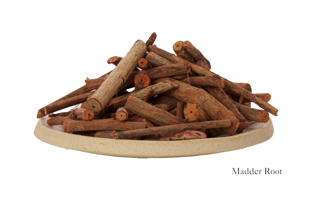 A plate filled with dried madder root pieces, labeled "Harda and Madder Root Ayurvedic Yoga Mat from Bennd Yoga," evokes the essence of a meditation space.