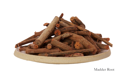 A plate filled with dried madder root pieces, labeled "Harda and Madder Root Ayurvedic Yoga Mat from Bennd Yoga," evokes the essence of a meditation space.
