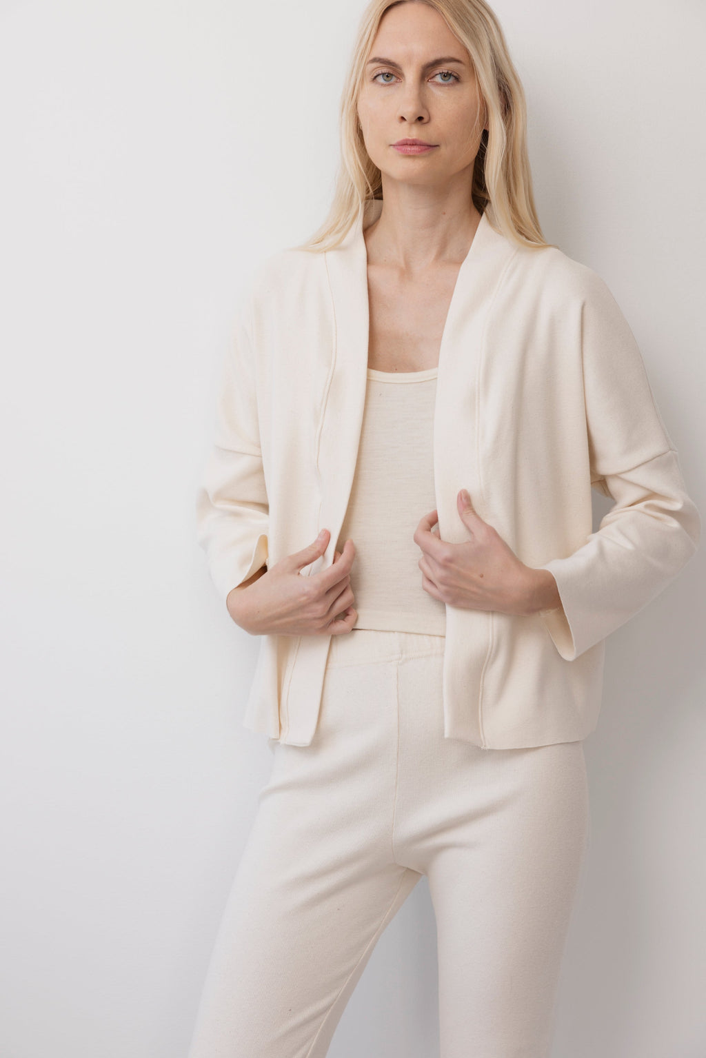 A woman with long blonde hair wears the Wol Hide Easy Cardigan in Natural, paired with matching pants, standing against a white background and looking at the camera with a neutral expression.