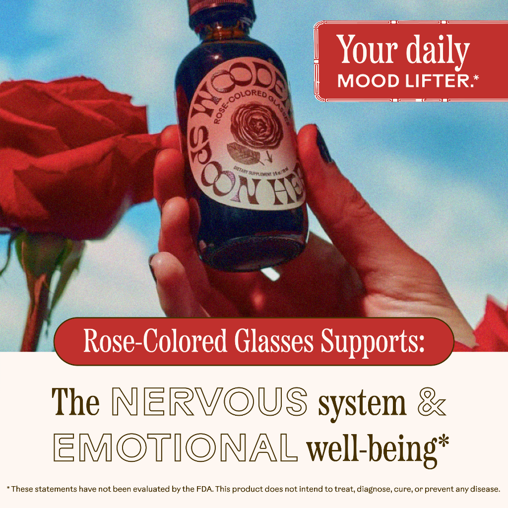 A hand holds a WOODEN SPOON HERBS "Rose-Colored Glasses" bottle in front of red roses. Text: "Your daily mood lifter." Below: "Rose-Colored Glasses supports stress relief and emotional well-being.