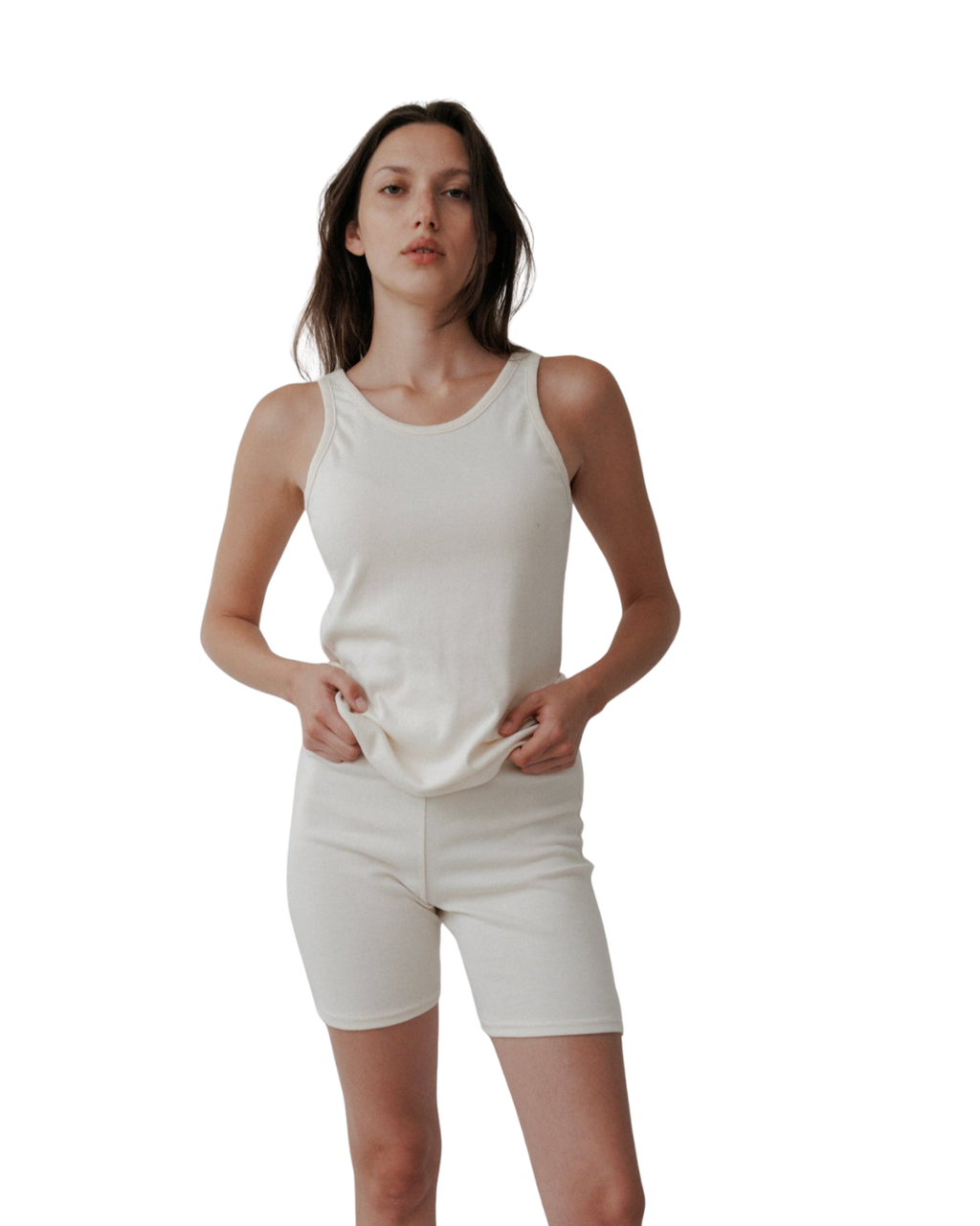 A woman poses confidently against a white backdrop wearing Wol Hide’s Scoop Back Rib Tank in Natural—an organic cotton, sleeveless piece that redefines modern, sustainable style.
