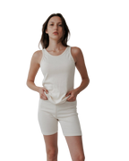 A woman poses confidently against a white backdrop wearing Wol Hide’s Scoop Back Rib Tank in Natural—an organic cotton, sleeveless piece that redefines modern, sustainable style.