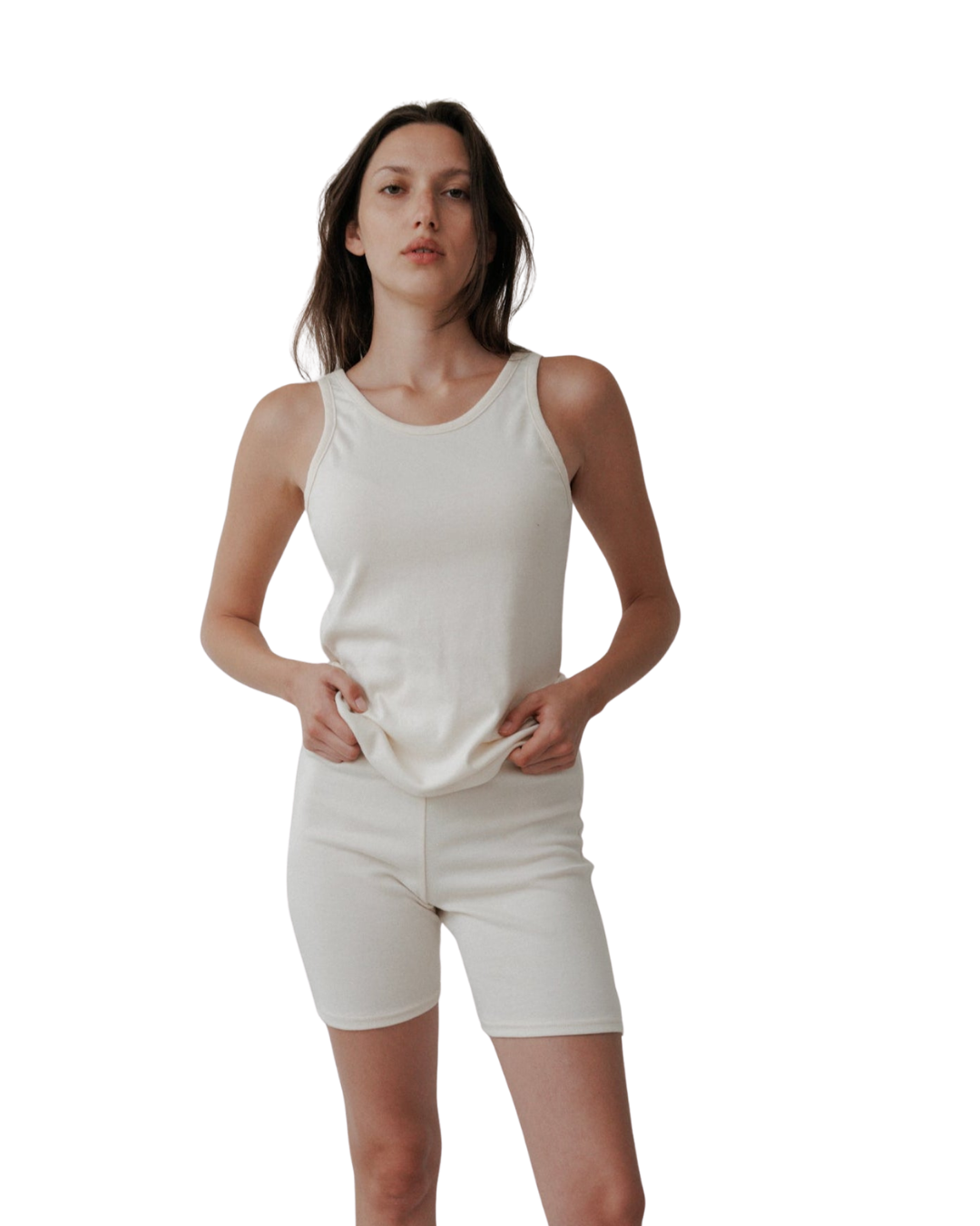 A woman poses confidently against a white backdrop wearing Wol Hide’s Scoop Back Rib Tank in Natural—an organic cotton, sleeveless piece that redefines modern, sustainable style.