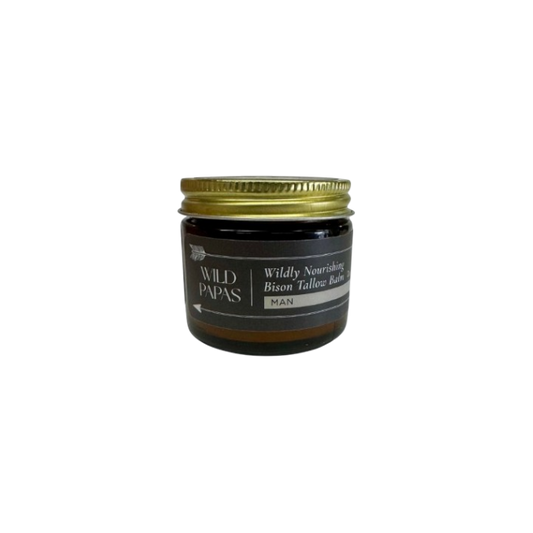 A small amber glass jar with a gold lid labeled "Wildly Nourishing Bison Tallow Balm - Man" by Wild Mamas features regenerative bison tallow, creating a premium men's balm, shown on a plain white background.