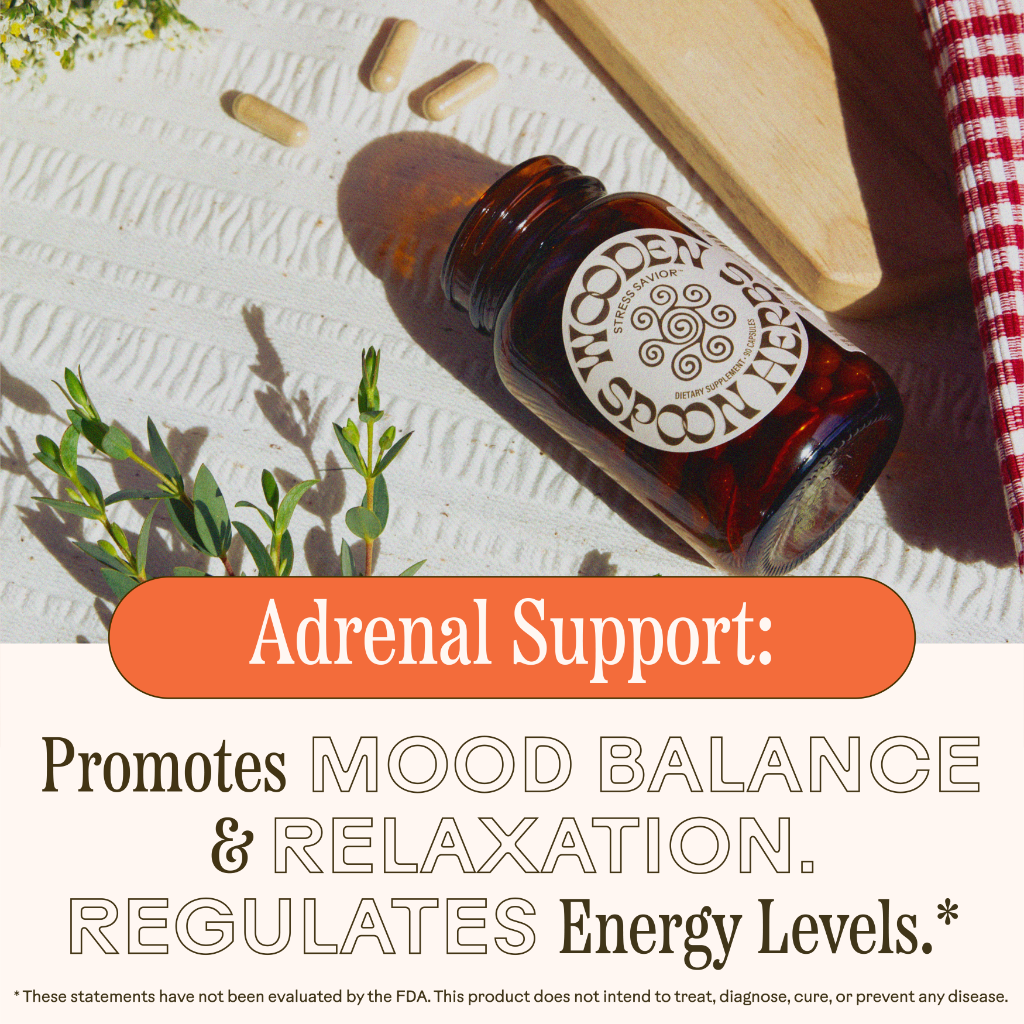 A brown WOODEN SPOON HERBS "Stress Savior" supplement bottle rests on a picnic cloth with pills, herbs, and sunlight. Text reads: “Adrenal Support: Promotes mood balance & relaxation with adaptogenic herbs for energy and stress relief.”.