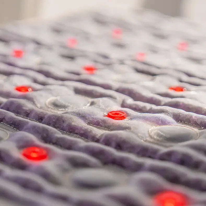 Close-up of a textured purple fabric featuring quilted waves and shiny red buttons, evoking the detailed design of HealthyLine's TAJ Series | PEMF Far Infrared Heating Mats for gemstone therapy.