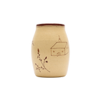 The Baile Homestead Vase by Baile is a handmade ceramic piece with a brown rim, beige surface, a simple house drawing, and hand-painted floral sprigs, shown against a plain white background.