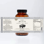 Amber bottle containing brown capsules, labeled "Family Multi-Wild Bison Organ Blend" by Wild Mamas. This whole food multivitamin features supplement facts for pasture-raised, prairie grass-fed wild bison organ and liver blend.