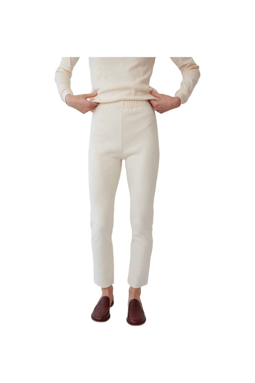 A person wears Wol Hide's Easy Legging in Natural—ivory heavyweight rib cotton, high-waisted—with a matching long-sleeve top and brown slip-on shoes. The face is not shown; only the body from shoulders to feet is visible on a plain white background.