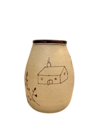 The Baile Homestead Vase by Baile is a cream-colored handmade ceramic vase featuring a simple line drawing of a house, chimney, and leafy branch, displayed against a plain white background.