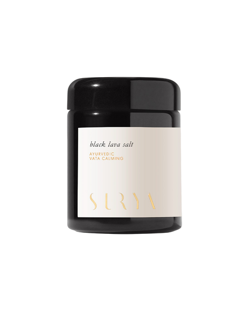 A black jar with a white label featuring "Black Lava Salt," "Ayurvedic salt," "Vata Calming," and the Surya brand name in gold, set against a plain, light background.