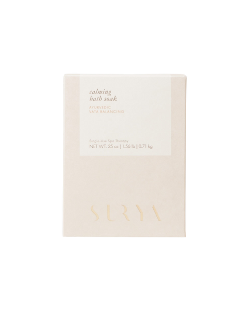 A beige 25 oz box labeled “Calming Bath Soak” by Surya features “Ayurvedic Vata Balancing,” is enriched with Ashwagandha, displays “Single Use Spa Therapy,” and has the brand name embossed at the bottom.