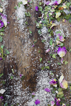 Surya’s Calming Bath Soak features white rice grains and vibrant dried lavender petals artfully arranged on rustic wood, creating a natural, textured display that evokes rejuvenation and tranquility.