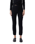 A person models Wol Hide's Easy Legging in Black—slim-fit heavyweight ribbed leggings—paired with a black long-sleeve top and black slip-on shoes, standing against a white background. The person's head is not visible.