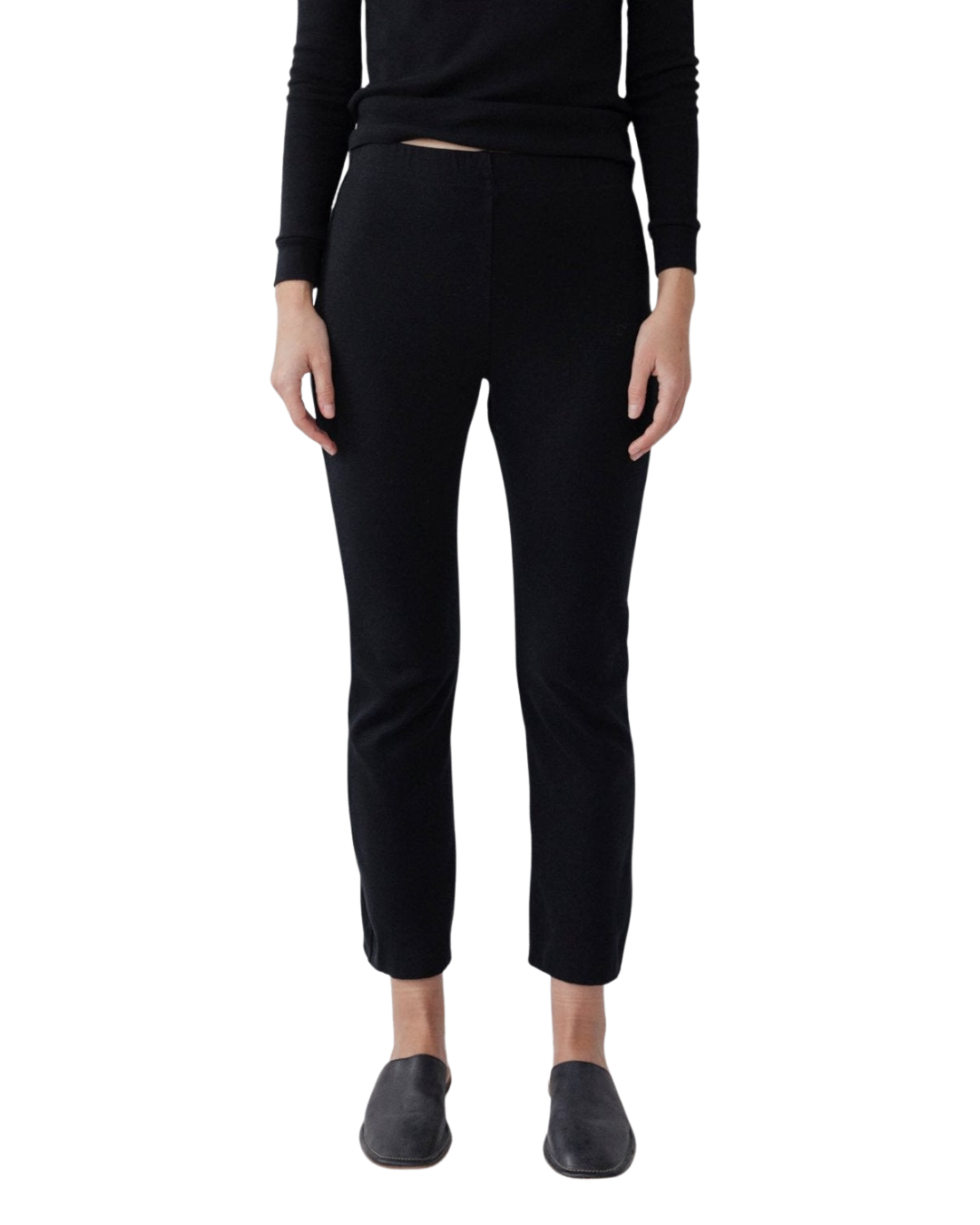 A person models Wol Hide's Easy Legging in Black—slim-fit heavyweight ribbed leggings—paired with a black long-sleeve top and black slip-on shoes, standing against a white background. The person's head is not visible.