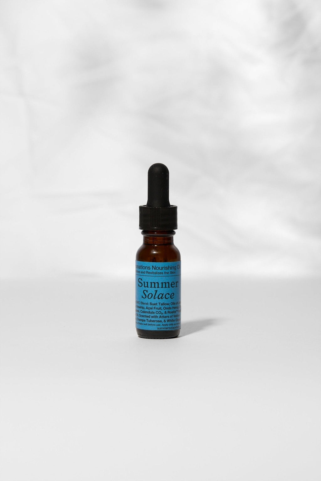 A small brown glass dropper bottle labeled "Summer Solace Tallow" with a blue label, containing Emanations Profound Face Oil—deeply nourishing tallow, emu oil, champa, tuberose & white ginger lily—stands on a white surface against a light gray background.