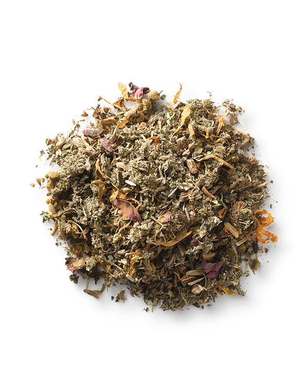 A small, clear glass bowl filled with Surya’s (y)oni Fertility Steam, a mix of dried Ayurvedic herbs and flowers. The blend features various shades of green, brown, and hints of pink and orange petals—an ideal preparation for pregnancy. The bowl is set against a white background.