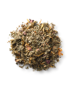 A small pile of Surya (y)oni Fertility Steam, a dried herbal blend with green, yellow, and pinkish flower petals and Ayurvedic herbs, is scattered on a white background.