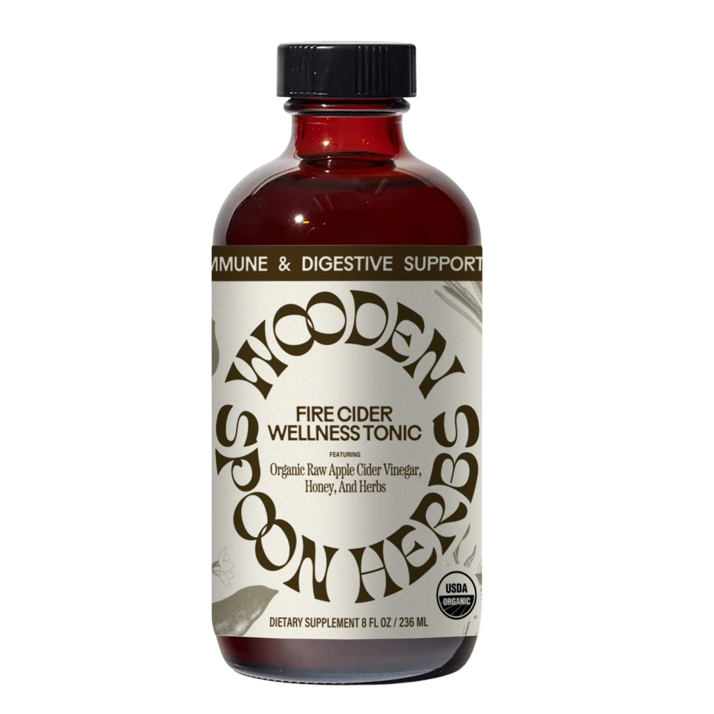 A brown glass bottle labeled “WOODEN SPOON HERBS Fire Cider,” made with organic apple cider vinegar, honey, and herbs. The USDA organic tonic offers immune and digestive support.