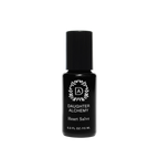 A small black bottle of Heart Salve® Botanical Nurturing Oil by Daughter Alchemy, crafted with organic ingredients, is displayed against a black background. The label features a white logo with a wreath design around the initials "DA" above the product name and indicates the bottle contains 0.3 fl oz (15 ml) of nurturing oil salve.