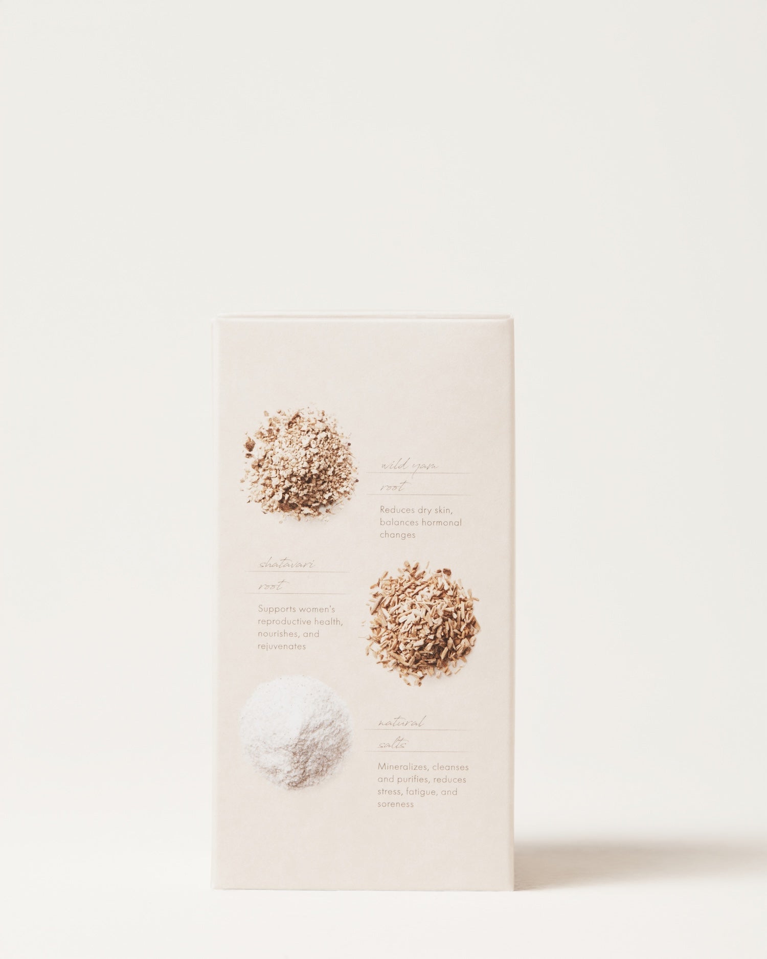 Surya's Hormone Soothing Bath Soak box displays wild yam root (light brown flakes) for hormone balance, salt (white crystals), and oatstraw (light tan strands) on a neutral backdrop.