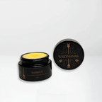 An open black jar with yellow balm inside, labeled "Golden C" by Wild Mamas and featuring gold text and feather designs, showcases its wild bison tallow blend for brightening vitamin C and collagen-supporting skincare benefits.