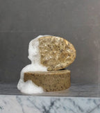 Two natural Wild Mamas soap bars, one oval and one round, stacked on dark gray marble with foamy suds. Featuring Shilajit + Decaffeinated Coffee Bean- Deeply Exfoliating Wild Bison Tallow Soap Scrub for sensitive skin.