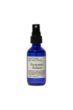 A blue glass spray bottle labeled "Jasmine Sambac + Magnolia Perfume Mist – Water-Based" by Summer Solace Tallow, with a black nozzle and a white label detailing ingredients and usage.