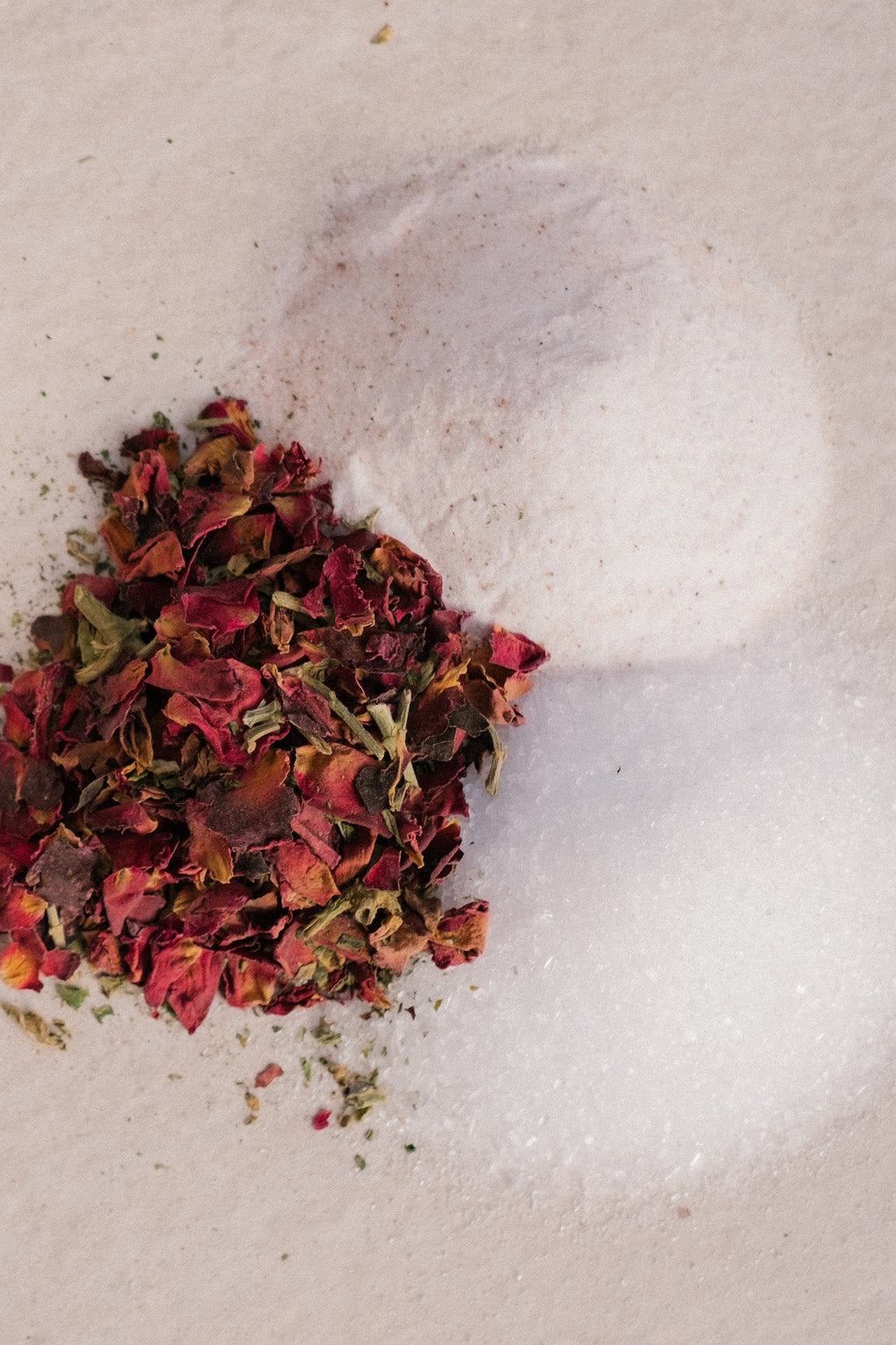 Surya’s Love Bath Heart-Opening Soak features dried rose petals, salt, and baking soda—perfect for a soothing, heart-opening bath experience. The ingredients are beautifully arranged on a light beige surface.