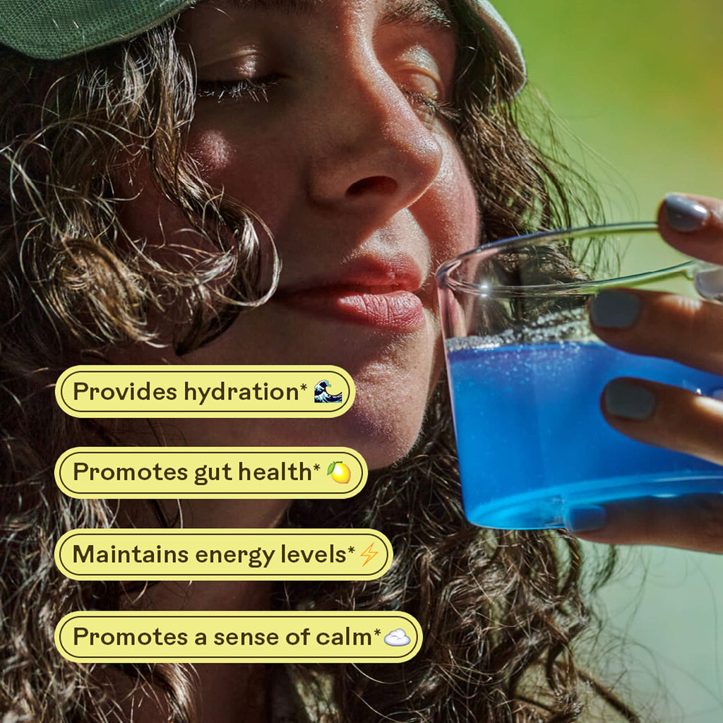 A woman with long curly hair and a cap drinks Magic Magnesium by WOODEN SPOON HERBS. Overlaid text: “Provides hydration,” “Promotes gut health,” “Maintains energy levels,” and “Magnesium Citrate promotes calm.”.
